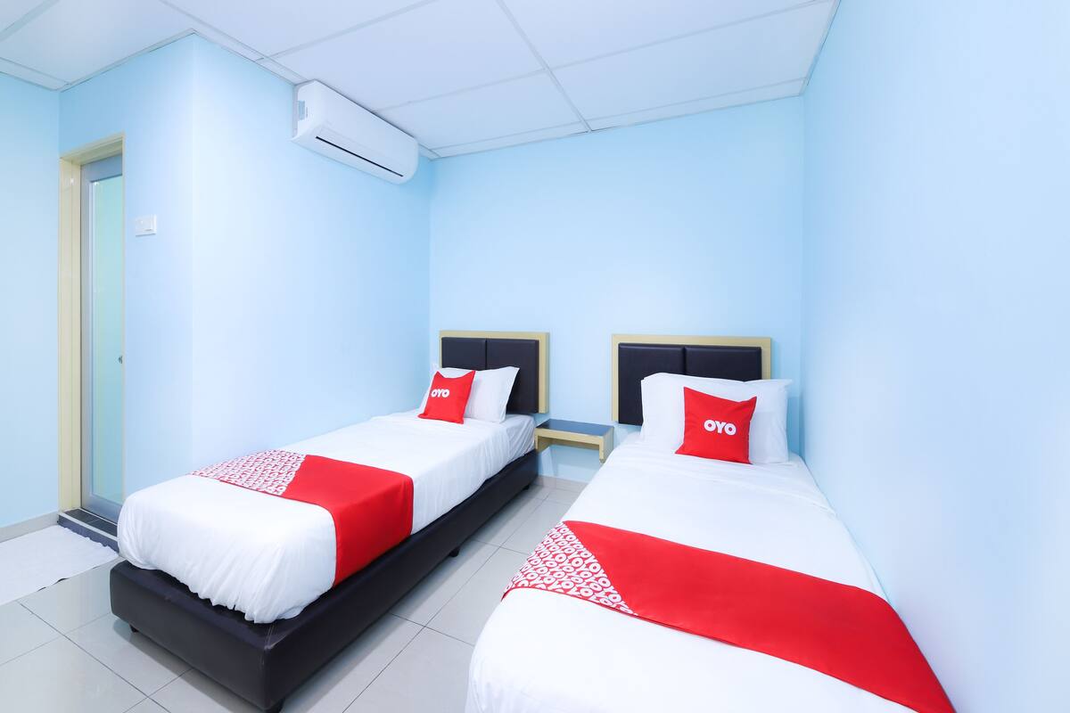 A hotel room with two beds, each with a white and red bedspread, and a red OYO branded pillow.