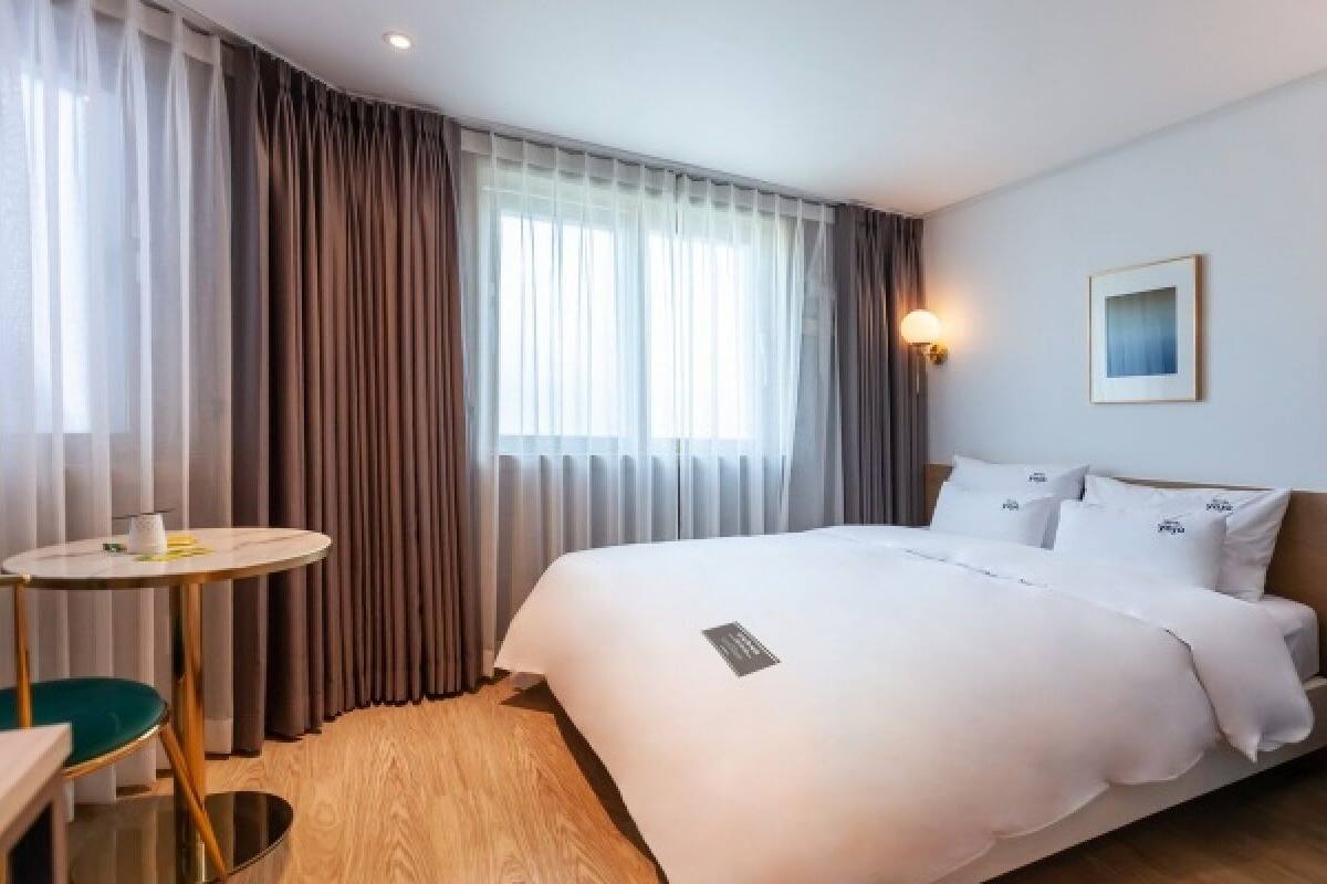 A hotel room with a bed, a small round table, and a chair.