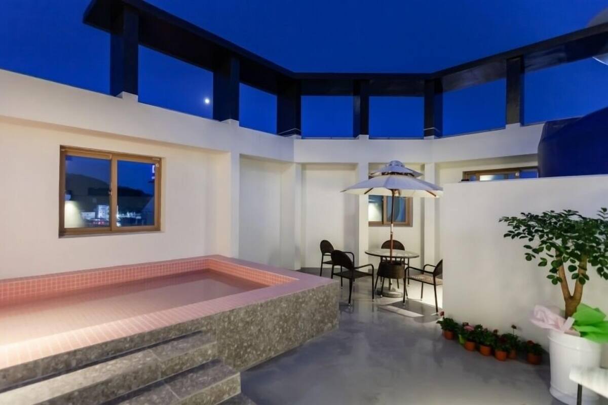 A rooftop terrace with a hot tub, outdoor seating, and potted plants.