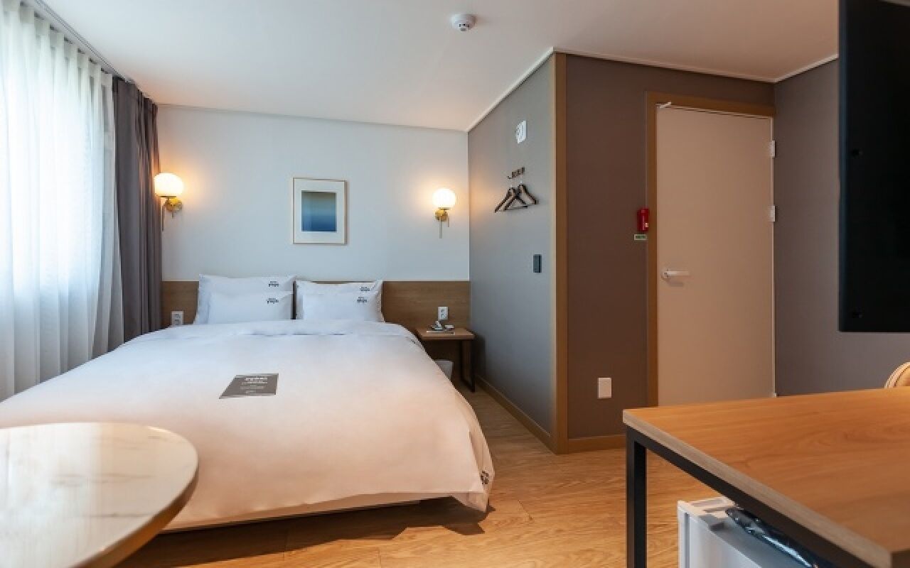 Een hotelkamer met een bed, nachtkastjes, een bureau en een stoel.