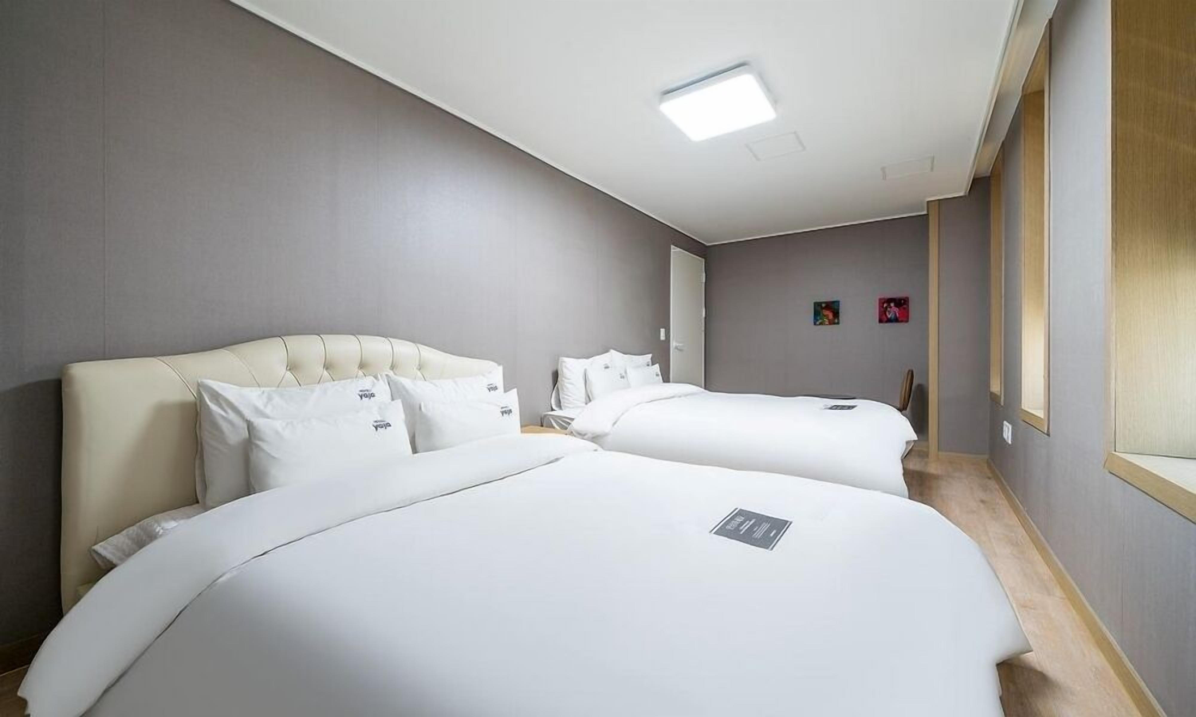 Habitación de hotel con dos camas, una lámpara en el techo y una ventana.