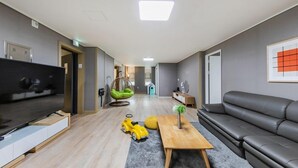 A modern living room with a flat-screen TV, a grey sofa, a wooden coffee table, and a yellow toy car. - YAJA Hotel Tongyeong Ferry Terminal Branch (Tongyeong)
