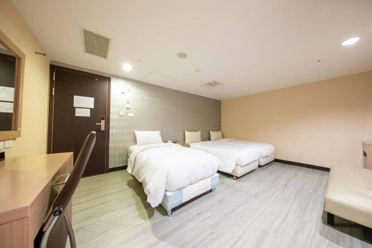 A hotel room with two beds, a desk, and a chair.