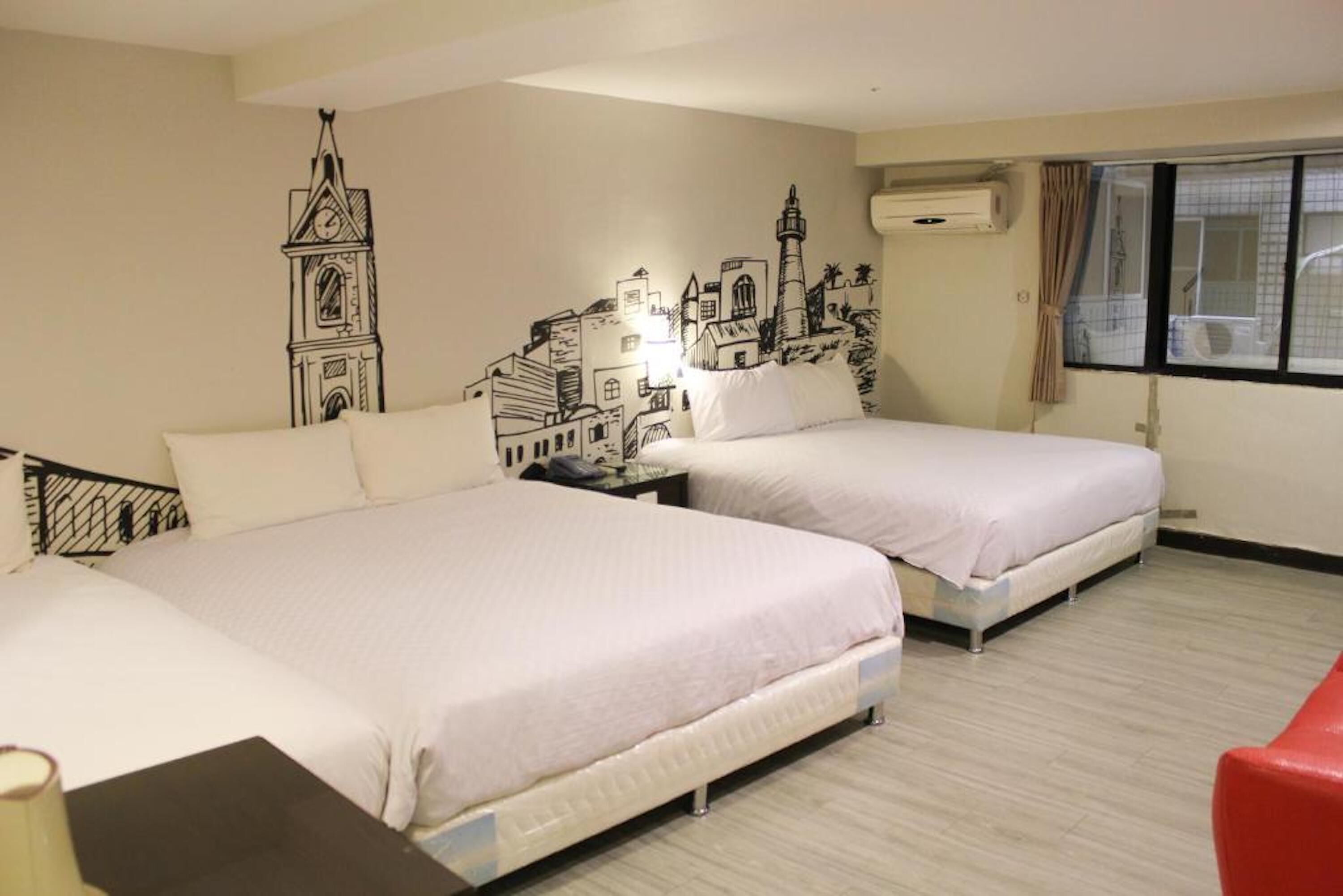 A hotel room with two beds, a nightstand, a lamp, and a red chair.