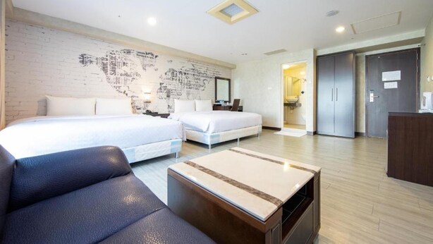 A modern hotel room with two beds, a sofa, a small table, and a world map on the wall. - Newhotel (Kaohsiung)
