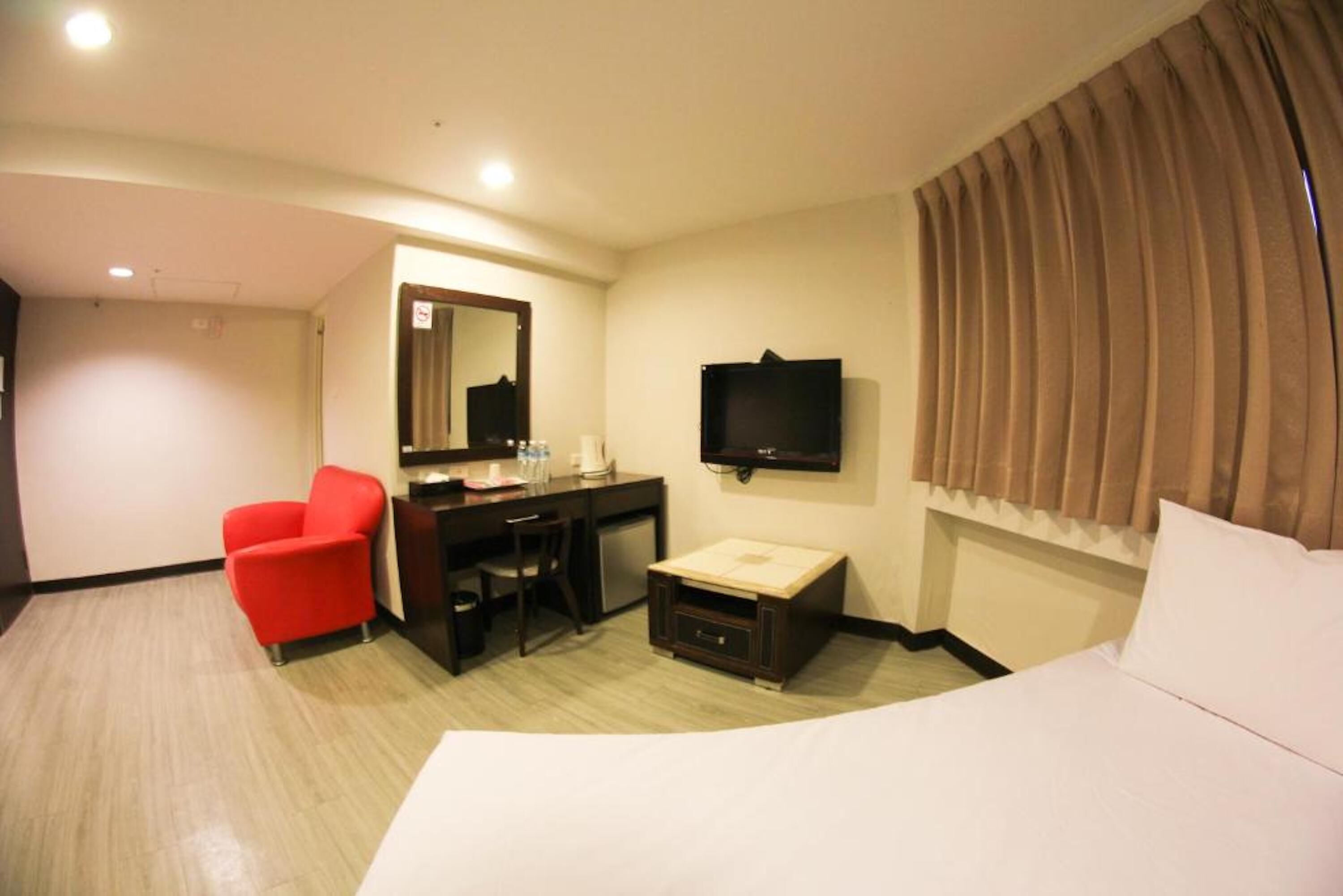 A hotel room with a bed, a desk, a chair, a television, and a window with curtains.