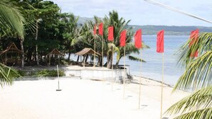 Una spiaggia con palme, una piccola capanna e bandiere rosse.