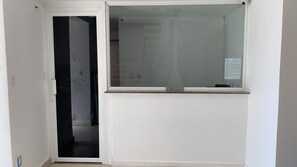 Une pièce avec une porte blanche, une fenêtre en verre et un petit tableau d’affichage accroché au mur.