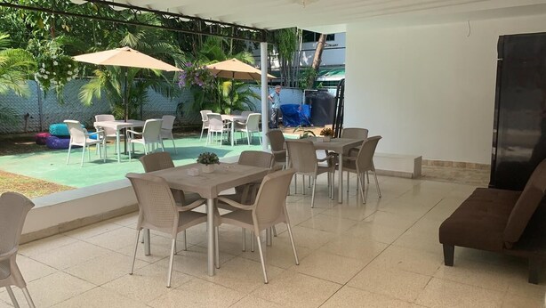 Un patio al aire libre con mesas y sillas, una piscina y una zona de estar cubierta.