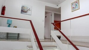 Una escalera con barandilla roja que lleva a un piso superior.
