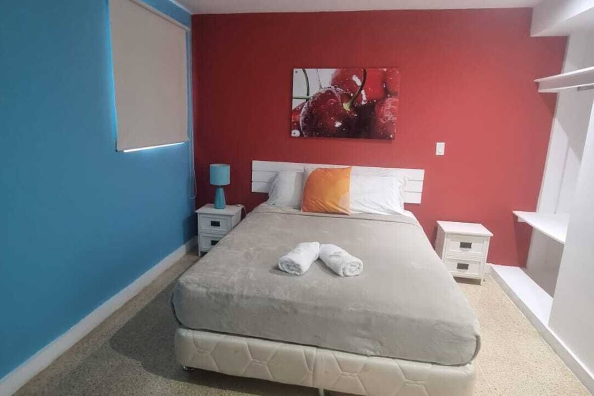 A bedroom with a bed, a nightstand, a lamp, and a painting on the wall.