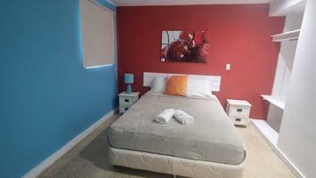 A bedroom with a bed, a nightstand, a lamp, and a painting on the wall.