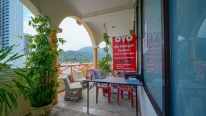 A balcony with a table, chairs, and a potted plant. A sign advertises a hotel and apartment with amenities like clean & fragrance, free WiFi, and fully air-conditioned rooms. - Hotel O My Budget Home (George Town)