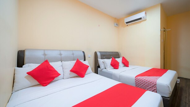Two beds with red pillows and a red bedspread, an air conditioning unit on the wall, and a shower area. - Hotel O My Budget Home (George Town)