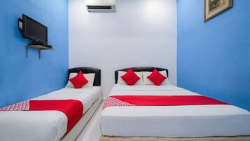 A hotel room with two beds, each with red and white bedding, a flat-screen TV on a stand, and an air conditioning unit on the wall.