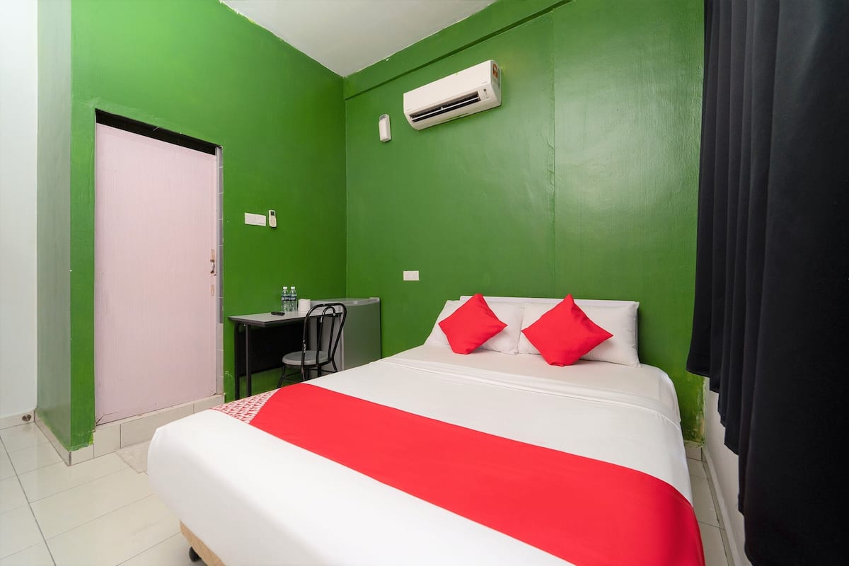 A room with a bed, a desk, and an air conditioning unit.