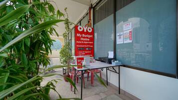 A hotel exterior with a red sign advertising OYO My Budget Home, a clean and fragrant environment, free WiFi, and fully conditioned rooms.