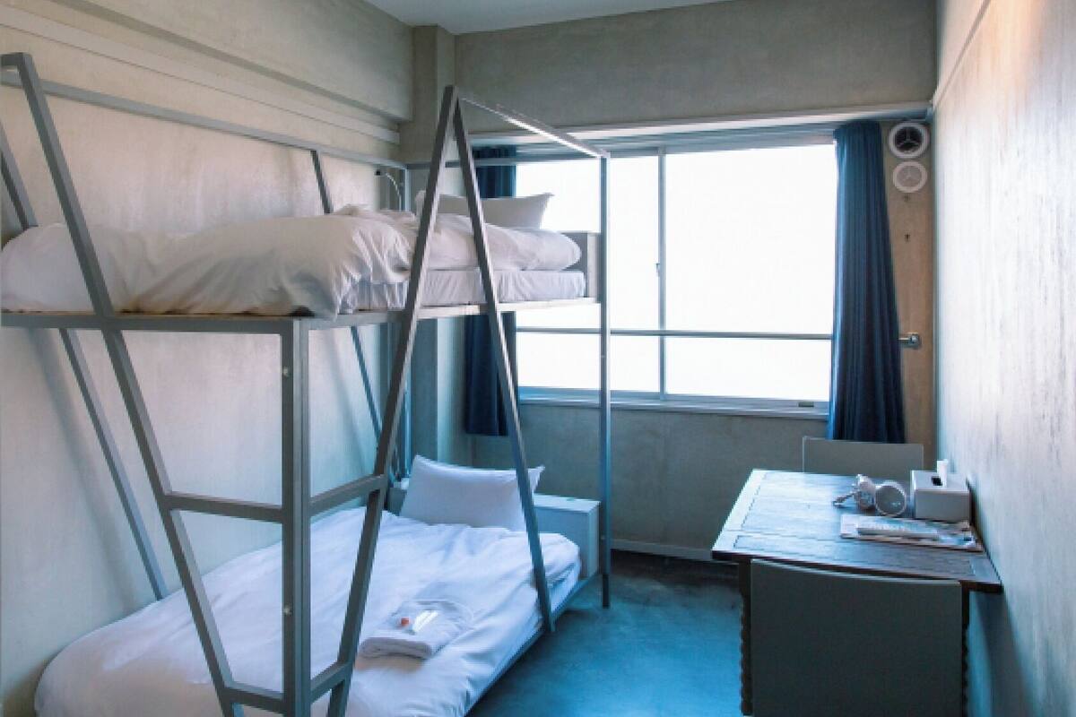 A bunk bed room with a desk and a window.