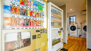Getränke und Snacks in Warenautomaten, eine Waschmaschine und ein Holzboden in einem Raum.