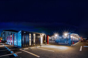 A modern hotel with a row of cabins, each with a glass facade and illuminated signage. - HOTEL R9 The Yard Yuki (Yuki)