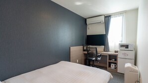 Ein Hotelzimmer mit Bett, Schreibtisch mit Stuhl, Mikrowelle, Kaffeemaschine und Fernseher.