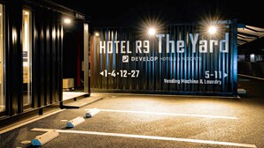 Ein moderner Hotelzugang mit einem Schild, das den Namen "HOTEL R9 The Yard" anzeigt, sowie Annehmlichkeiten wie einen Getränkeautomaten und eine Wäscherei.