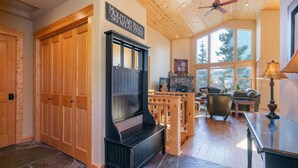 A cozy living room with a fireplace, wooden furniture, and large windows offering a view of trees. - 5bd3ba, sleeps 10 Mountain View Hot Tub/Poker/Pool table, near Ski Resort (Truckee)