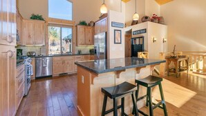 A spacious kitchen with wooden cabinets, a central island with stools, and pendant lighting. - 5bd3ba, sleeps 10 Mountain View Hot Tub/Poker/Pool table, near Ski Resort (Truckee)