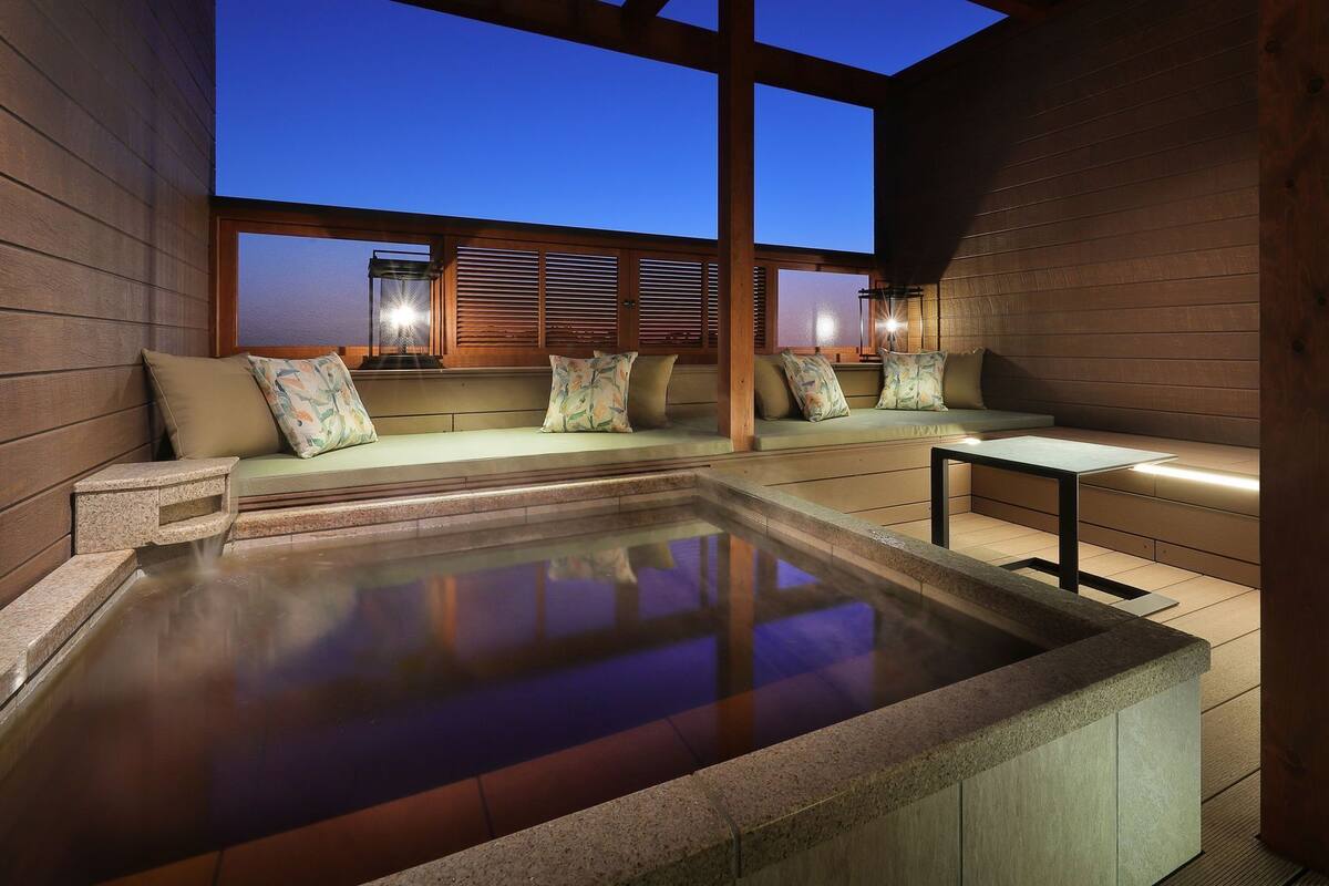 A hot tub area with seating and a view of the sky.