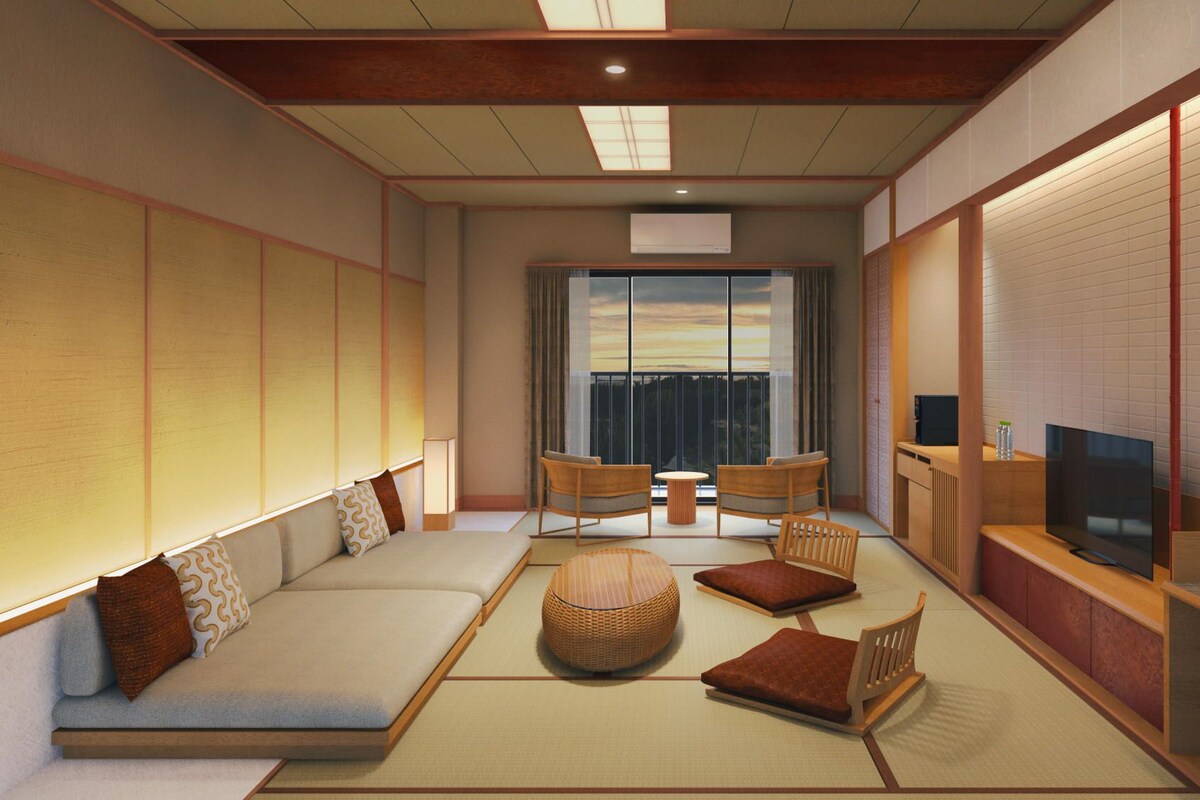 Ein traditioneller japanischer Wohnraum mit Tatami-Bodenbelag, einem niedrigen Tisch, zwei Sofas und einem Fernseher.