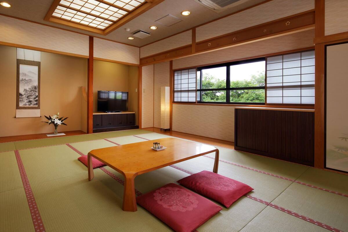 A traditional Japanese room with tatami flooring, a low wooden table, and a television.