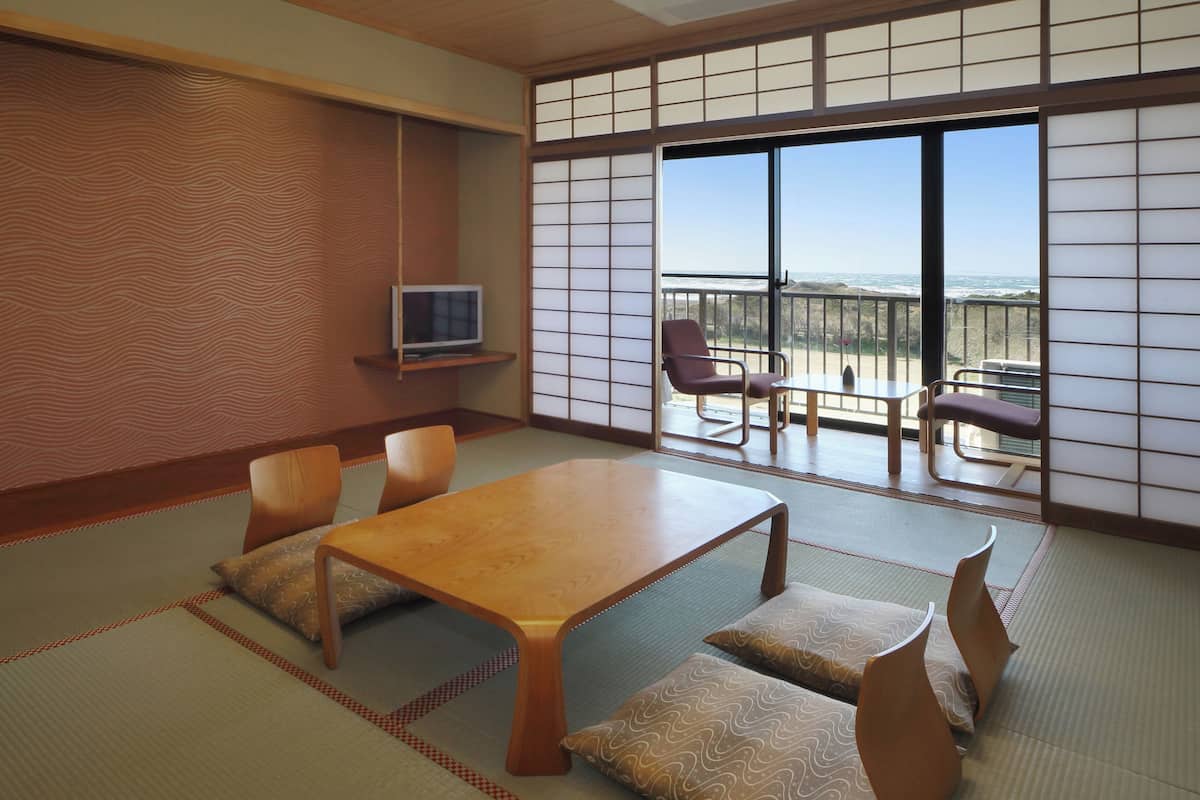 A traditional Japanese room with tatami flooring, a low table, and a TV on a shelf.