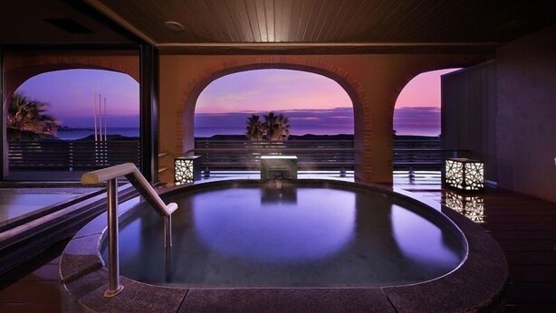 A hot tub with a view of the sunset through arched windows. - Tateyama Onsen Senri no Kaze (Tateyama)