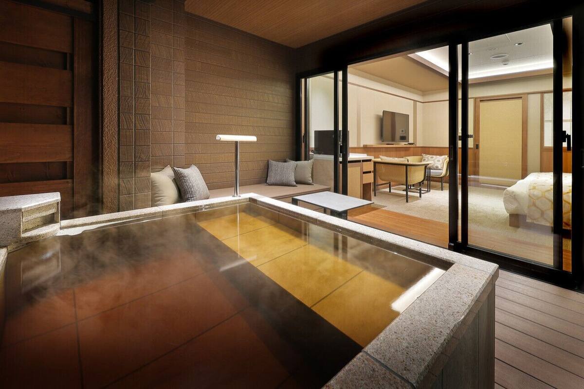 A modern spa area with a hot tub, seating, and a view into a room with a TV.