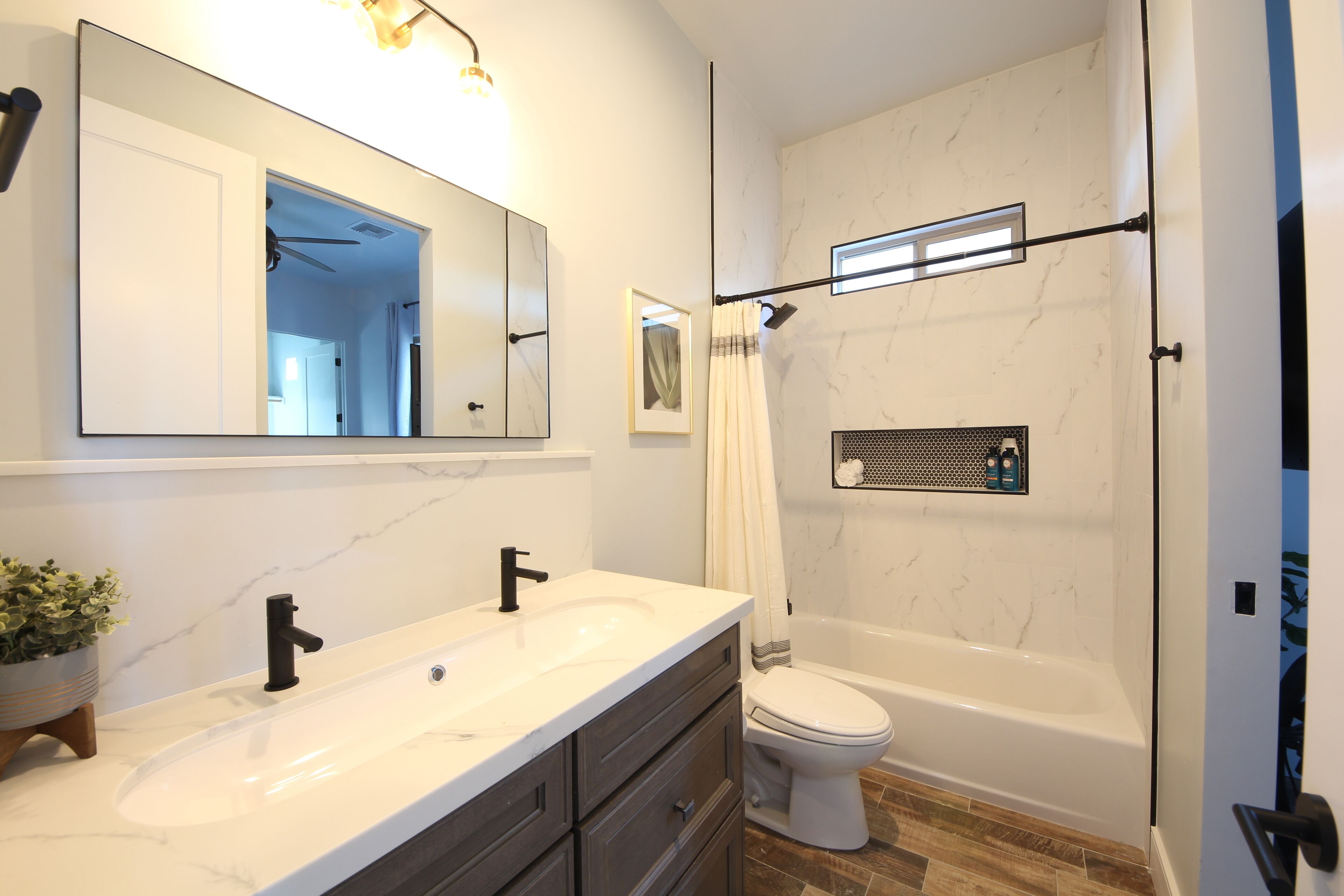 Een moderne badkamer met een grote spiegel, twee wastafels, een toilet en een bad.