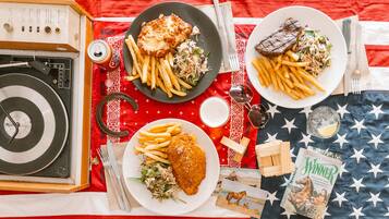 Una mesa con dos platos de comida, una radio antigua y una colección de postales antiguas.