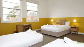 Une chambre d’hôtel avec deux lits, un bureau et une fenêtre donnant sur l’extérieur.
