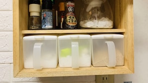 A wooden shelf with various kitchen items including bottles, a glass jar with ice, and plastic containers. - YokohamaKannai HouseBar (Yokohama)