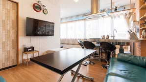 A modern kitchen with a dining area, a TV mounted on the wall, and a sofa. - YokohamaKannai HouseBar (Yokohama)