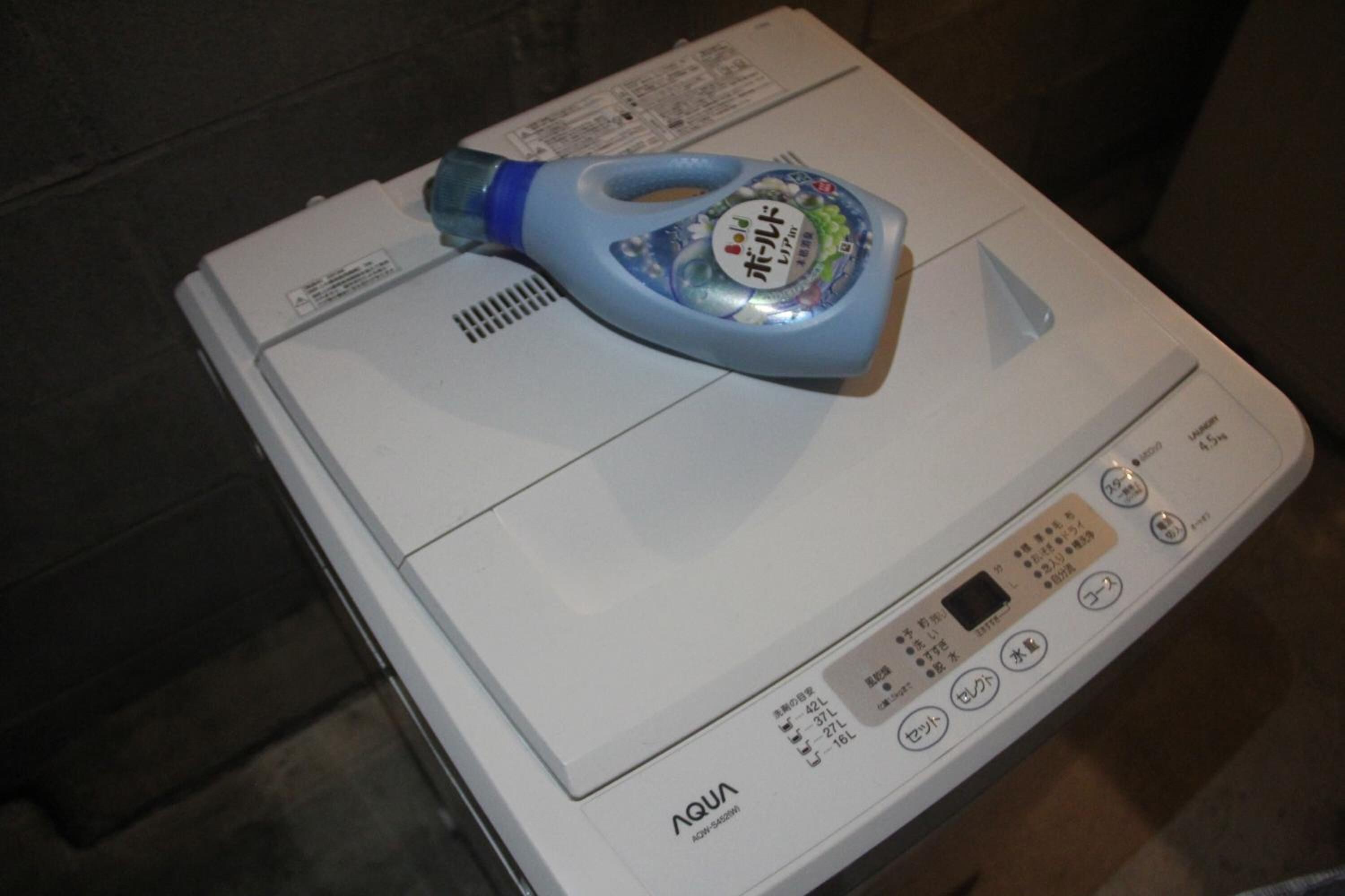 A white washing machine with a blue detergent bottle on top.