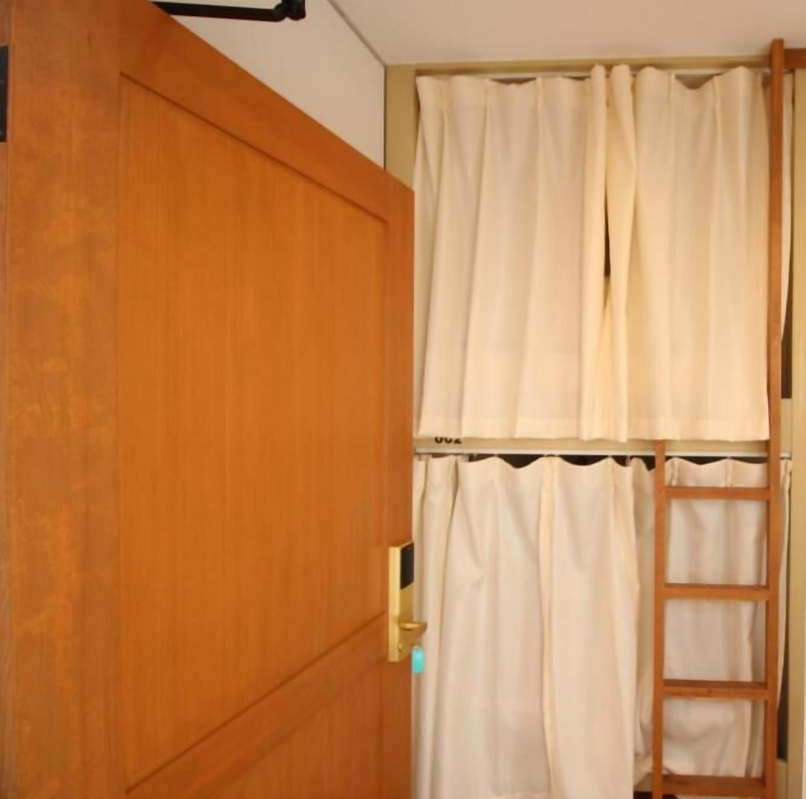 A wooden door with a metal handle, a white curtain, and a wooden ladder leaning against the wall.