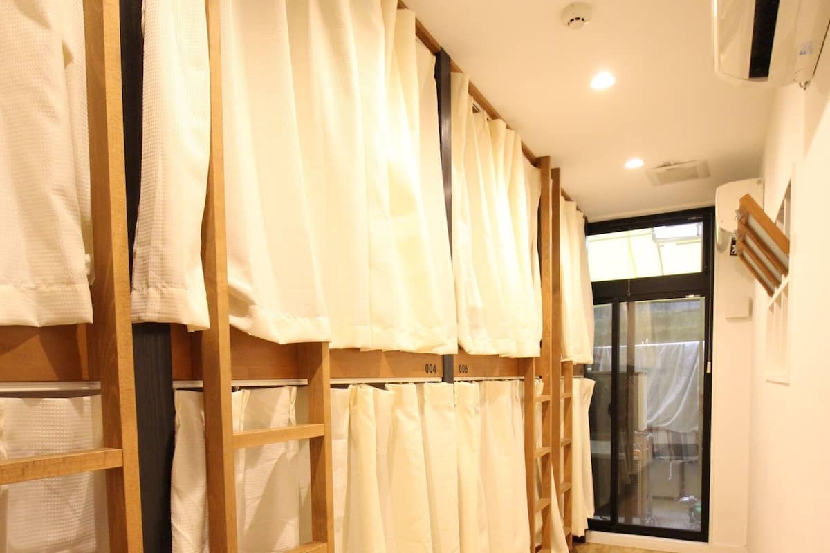 A hallway with wooden flooring and a series of white curtains on wooden racks.