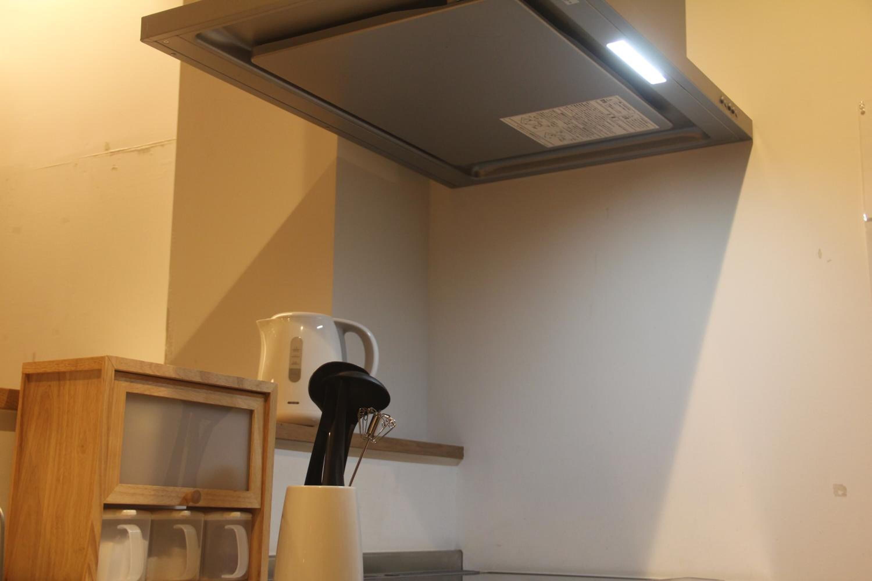 Una cocina con campana extractora de acero inoxidable, un mueble de madera y una cafetera.