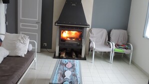 A living room with a wood-burning stove, a sofa, two chairs, and a coffee table. - beautiful ronçoise villa for 7 people near the beach and shops (Ronce-les-Bains)