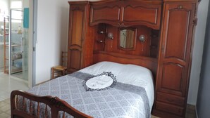 A bedroom with a wooden bed frame, a bedside table, and a wardrobe. - beautiful ronçoise villa for 7 people near the beach and shops (Ronce-les-Bains)
