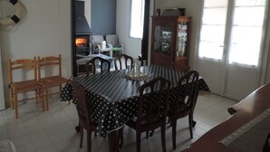 A dining area with a table set for four, surrounded by wooden chairs. There is a cabinet with glass doors to the right. - beautiful ronçoise villa for 7 people near the beach and shops (Ronce-les-Bains)