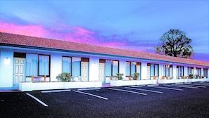 Un motel con una fila de habitaciones, cada una con ventana y un pequeño porche.