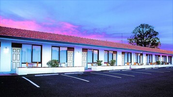 Un motel con una fila de habitaciones, cada una con ventana y un pequeño porche.
