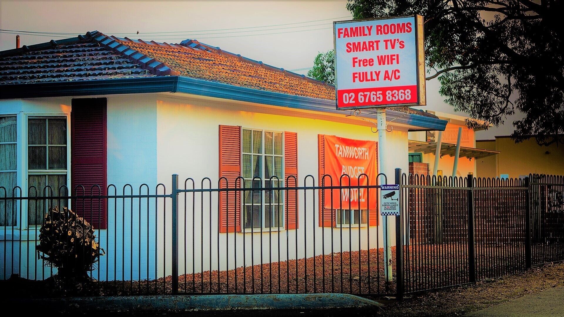 Un motel con un letrero que anuncia habitaciones familiares, televisores inteligentes, WiFi gratuito y habitaciones con aire acondicionado.