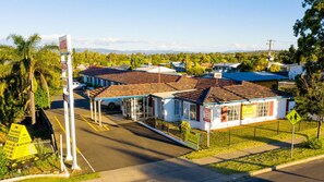 A motel with a fenced parking area, a single-story building, and a clear view of the surrounding landscape. - Tamworth Budget Motel (South Tamworth)